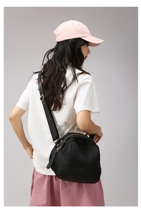 Détail de la bandoulière réglable et de la forme du sac à bandoulière en nylon noir sur modèle