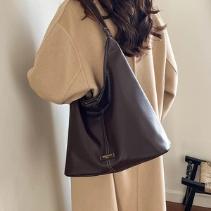 Detail of dark brown hobo bag featuring contrast white stitching and leather brand tag