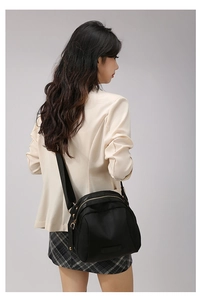 Vue latérale du sac bandoulière en nylon noir avec zips dorés sur mannequin