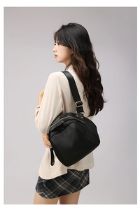 Vue latérale du sac bandoulière en nylon noir avec détails dorés et large sangle