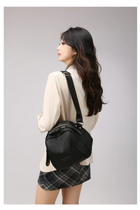 Vue latérale d'un sac bandoulière en nylon noir avec détails dorés porté par un mannequin