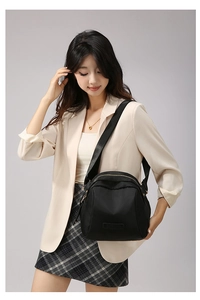 Détail du sac bandoulière en nylon noir avec fermeture éclair dorée et large bandoulière