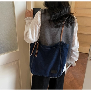 Detailed view of dark blue denim tote bag with brown braided rope shoulder straps