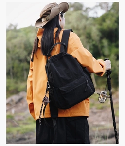 Detail of black nylon backpack with trekking pole attachment in outdoor forest setting
