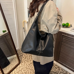 Detail view of large black leather hobo bag featuring stylish contrast white stitching