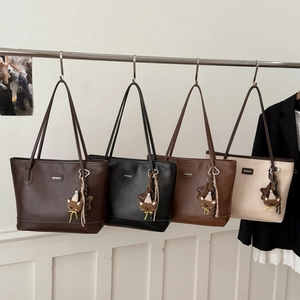 Retro tote bags in four colors hanging on a rack with cute bear charms and brand logo