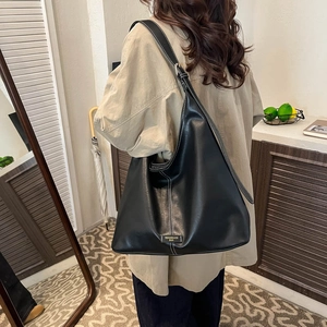 Detail of black matte leather tote bag featuring white contrast stitching and logo