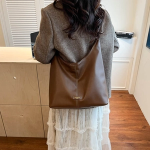 Detailed view of brown leather tote with white contrast stitching and logo label