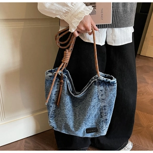 Détail du grand sac cabas en jean bleu avec anses en corde tressée et patch en cuir