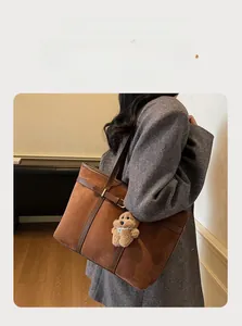 Detail of vintage dark brown suede tote bag with leather trim and plush bear charm