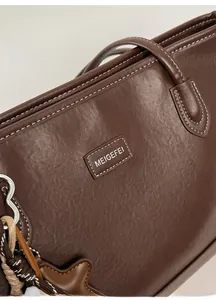 Detailed view of dark brown tote bag with contrast stitching and star charm detail