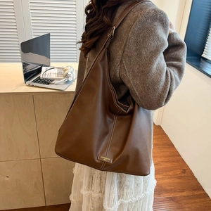 Detailed view of brown PU leather hobo bag with contrast stitching on model side