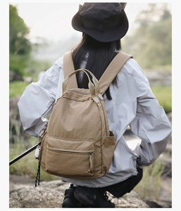 Rear view of model wearing a khaki outdoor backpack in a natural forest setting