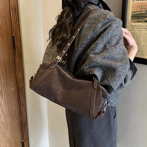 Detail einer dunkelbraunen Vintage-Lederschultertasche mit Metallschnalle am Modell