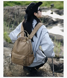 Khaki outdoor backpack on model in natural landscape, durable fabric detail