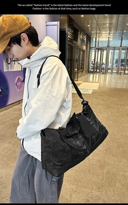 Man carrying a black large-capacity travel bag with textured surface and adjustable strap