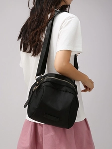 Sac bandoulière multifonctionnel en nylon noir avec détails dorés porté par un mannequin