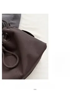Dettaglio in pelle marrone scuro con trama litchi, coulisse e occhielli argentati