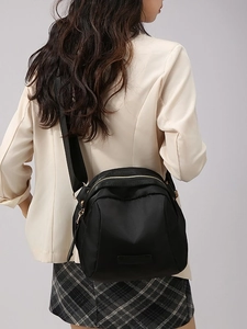 Sac de poitrine en nylon noir avec fermetures éclair dorées porté par un mannequin