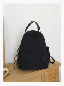 Detail view of water-resistant black nylon backpack with a decorative owl keychain