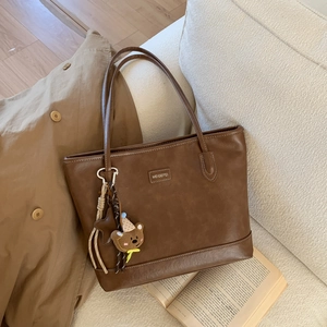 Detail of vintage brown tote bag with stitching and a cute bear plush keychain