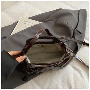 Detail view of the brown patent leather tote bag interior with magnetic closure and strap