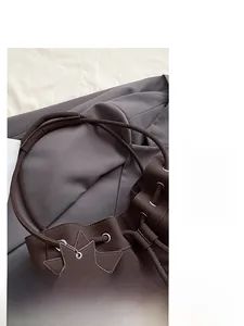 Dettaglio della borsa a secchiello in pelle marrone scuro con grana litchi e ciondolo