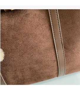 Close-up of brown suede tote bag featuring premium leather trim and precise stitching detail
