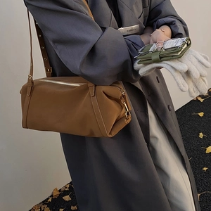 Detail einer karamellbraunen zylindrischen Ledertasche mit silbernen Beschlägen an der Schulter