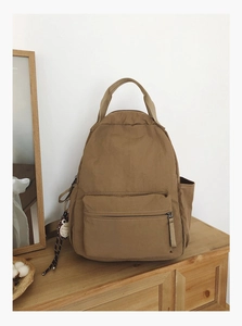 Detail view of khaki casual backpack with large main compartment and owl charm