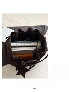 Vista dall'alto della capiente borsa a secchiello marrone scuro con oggetti personali