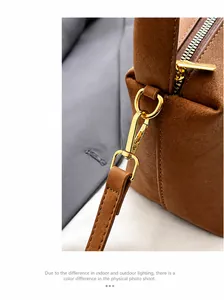 Dettaglio macro del gancio in metallo dorato e della zip sulla borsa in pelle marrone