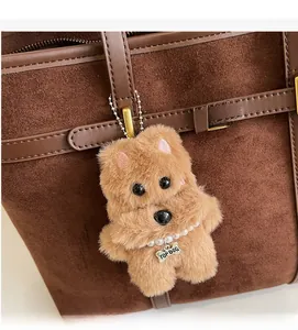 Detail of a brown plush dog charm with a Top Dog bone tag on a suede tote bag