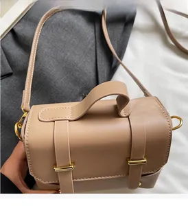 Detail of beige faux leather square handbag showing the gold hardware and top handle