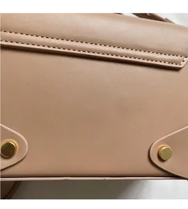 Detailed close-up of light brown leather texture with precise stitching and gold studs