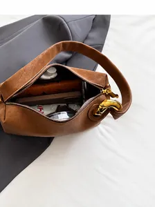 Interno spazioso della borsa a spalla in pelle marrone con oggetti quotidiani e ombrello