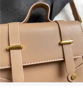 Detailed close-up of a beige textured handbag with gold hardware and white stitching