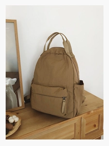 Macro shot of khaki waterproof nylon backpack showing front zipper pocket and side pocket