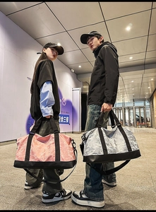 Detail view of large travel bags in pink and silver with reinforced handles and straps
