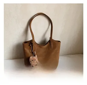 Détail du sac cabas en similicuir marron avec breloque ours en peluche et glands