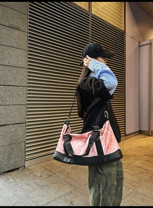 Outdoor model shot of a pink marble print travel bag with black straps and metal hooks