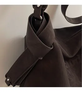 Détail du sac cabas en daim marron avec bandoulière nouée et rivets argentés chic