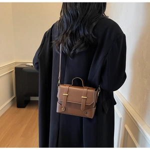 Detail of vintage brown crossbody bag with matte texture and gold metal accents