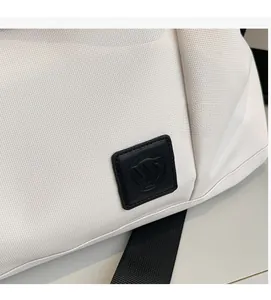 Close-up of white nylon travel bag texture with a black square geometric logo patch