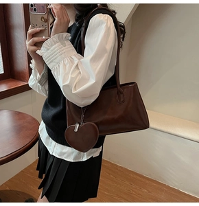 Detail of dark brown oil-wax leather tote bag with heart-shaped coin purse on a model
