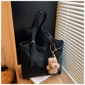 Détail du grand cabas noir en similicuir avec boucles dorées et breloque ours sur bois
