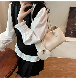 Detail of cream leather shoulder bag featuring a matching heart-shaped pendant accessory