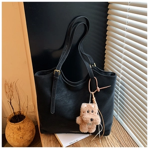 Détail d'un grand cabas en cuir mat noir avec sangles réglables et charm chien peluche
