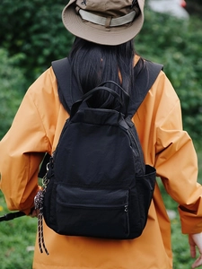 Black lightweight nylon outdoor backpack for travel and hiking on a male model