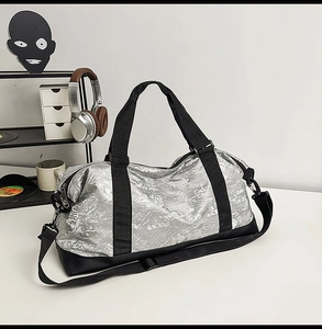 Close-up of metallic silver duffel bag featuring dual webbing handles and adjustable strap